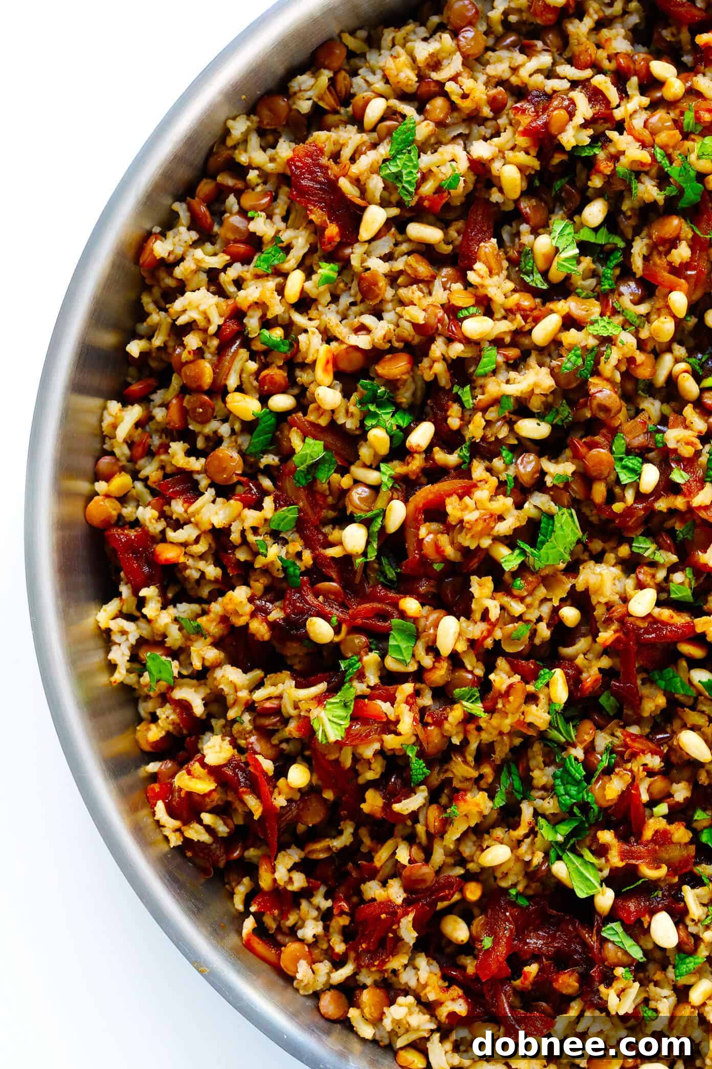 Mujadara being mixed with fresh mint and pine nuts.