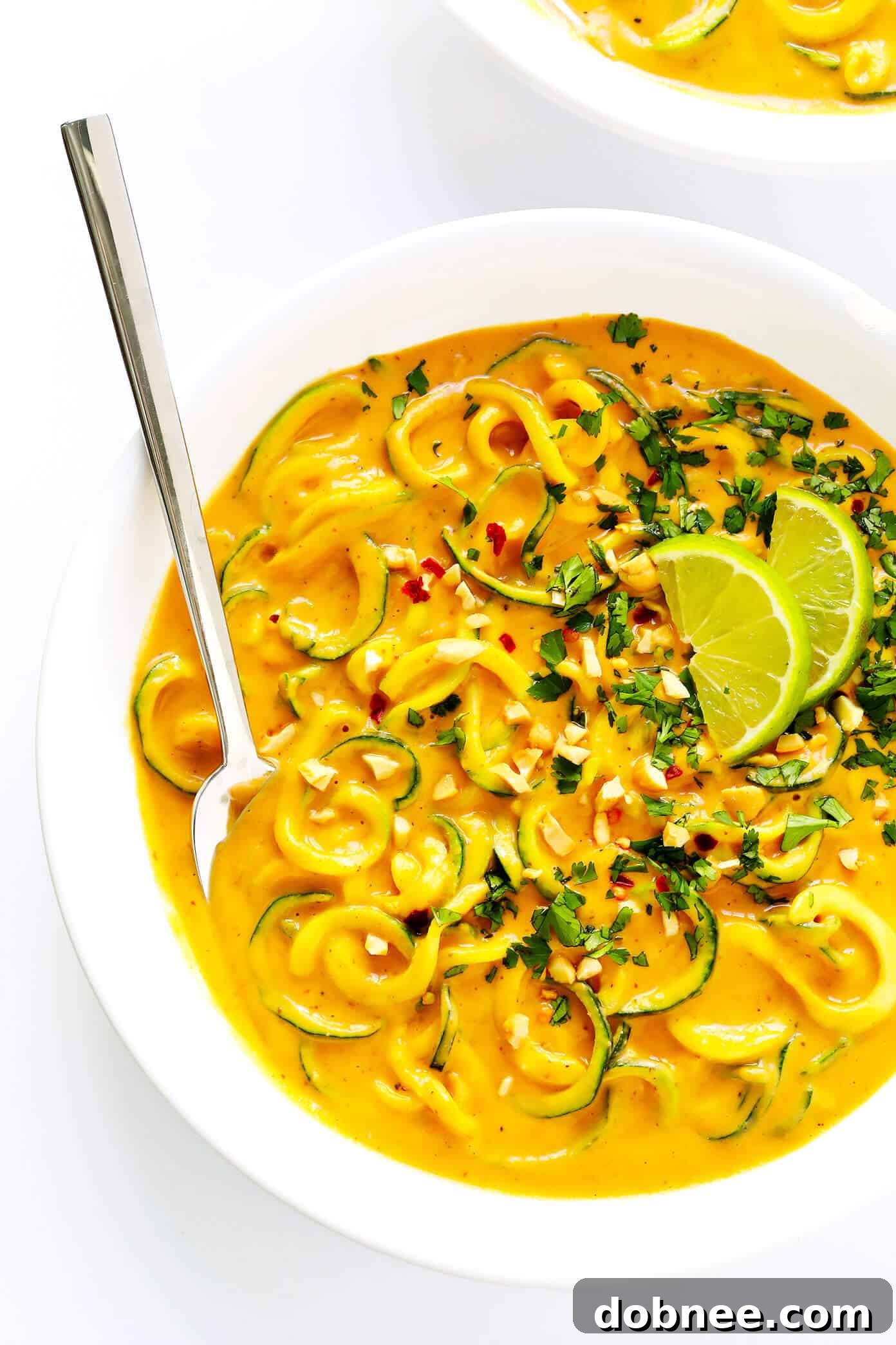 Delicious Curried Satay Veggie Bowls with Zucchini Noodles, garnished with fresh herbs and nuts