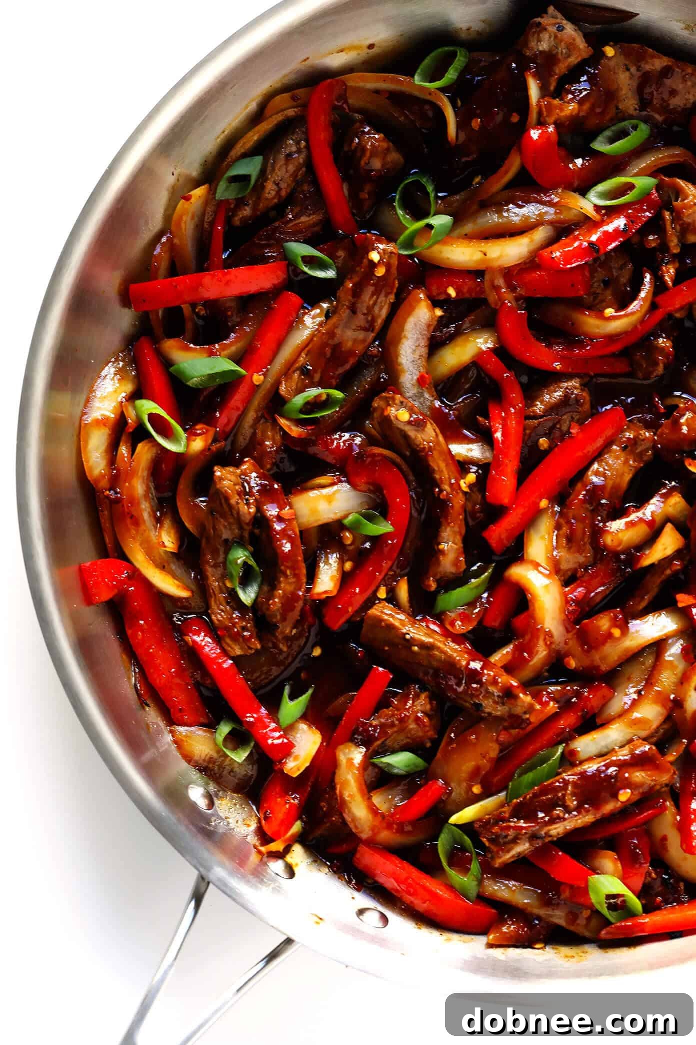 Close-up of Sizzlin' Spicy Szechuan Stir-Fry with steak, bell peppers, and onions, glistening with sauce.
