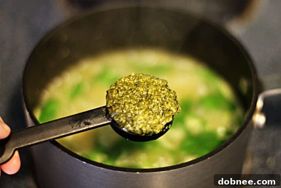 A close-up view of the White Bean, Spinach & Pesto Soup, highlighting the creamy texture of the beans and the vibrant green of the spinach and pesto, ready for serving.