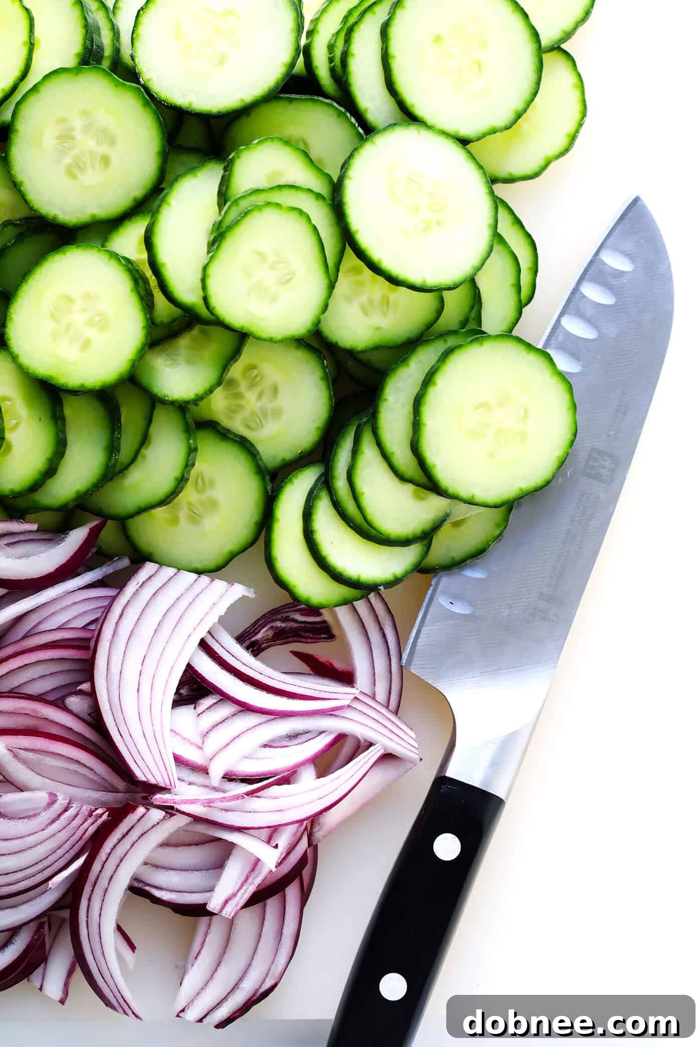 Slicing fresh English cucumber and red onion for a vibrant side salad