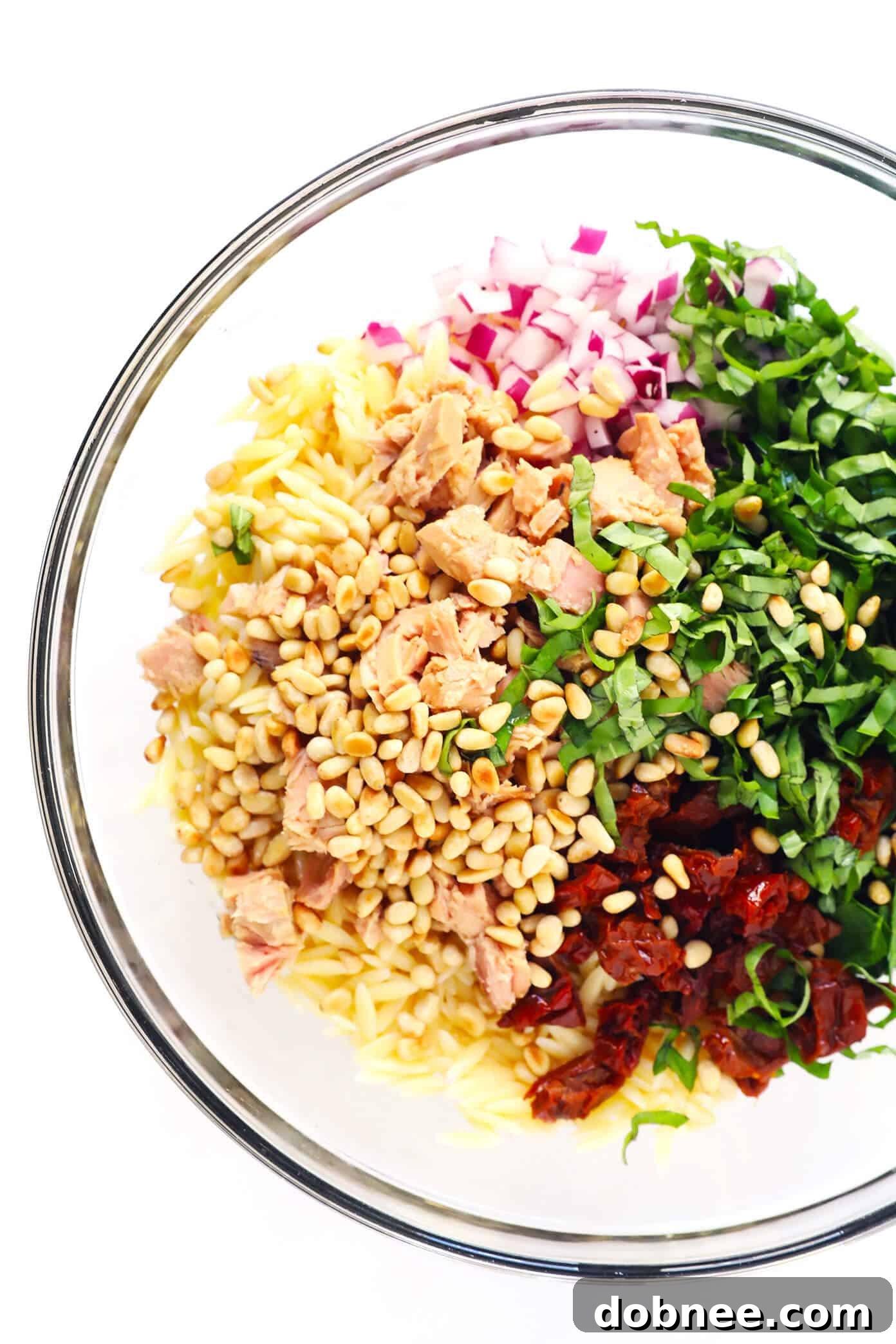 Italian Orzo Tuna Salad Ingredients — fresh basil, sun-dried tomatoes, feta cheese, and pine nuts ready for a vibrant pasta salad.