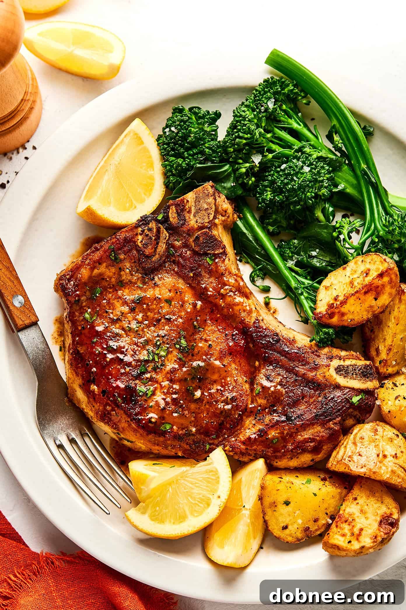 A plated meal of baked pork chops with a fresh salad and roasted potatoes.
