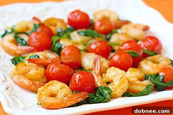 Close-up of vibrant sautéed shrimp with spinach and cherry tomatoes in a pan, ready to serve.