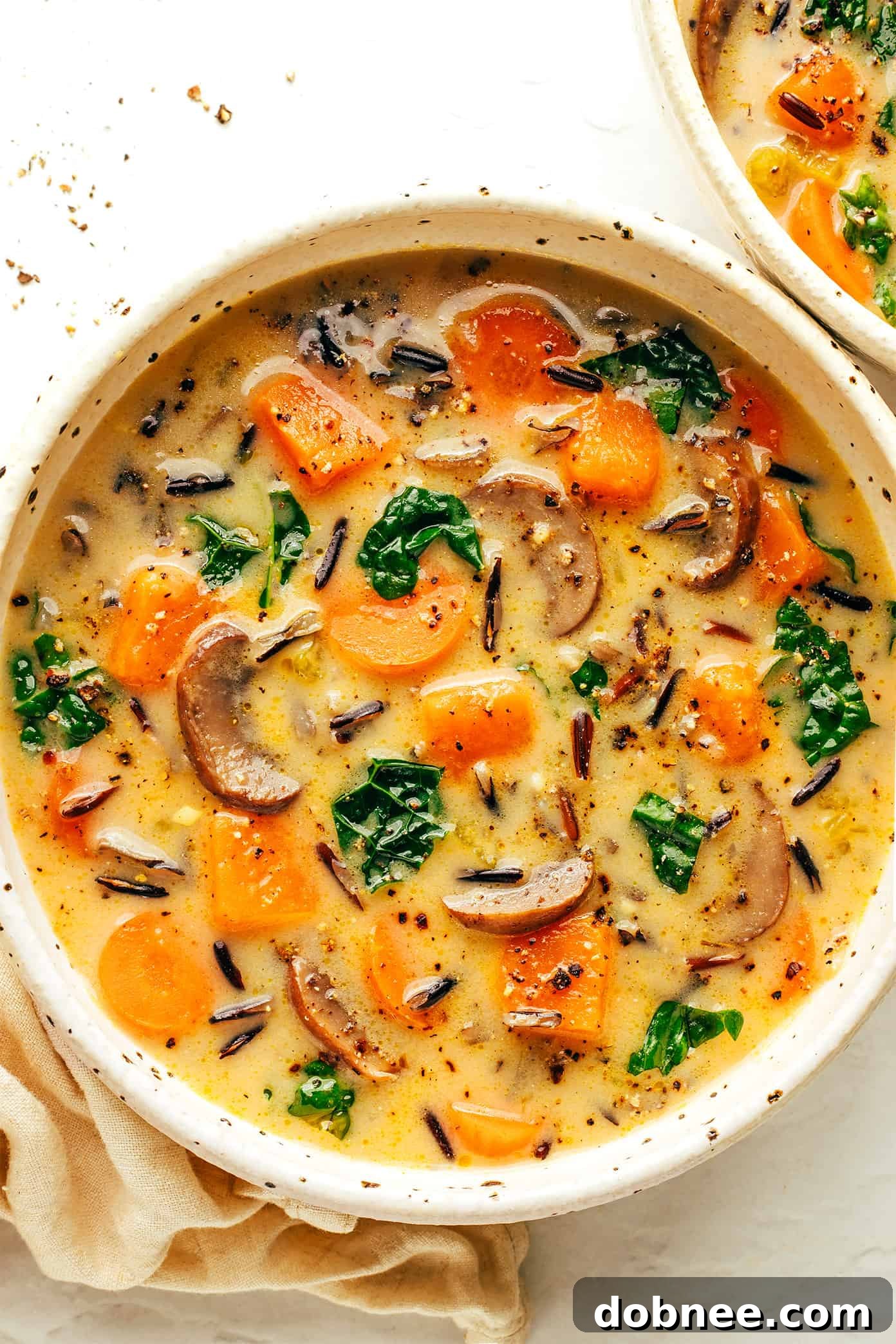 Cozy Autumn Wild Rice Soup in a bowl with crusty bread and herbs
