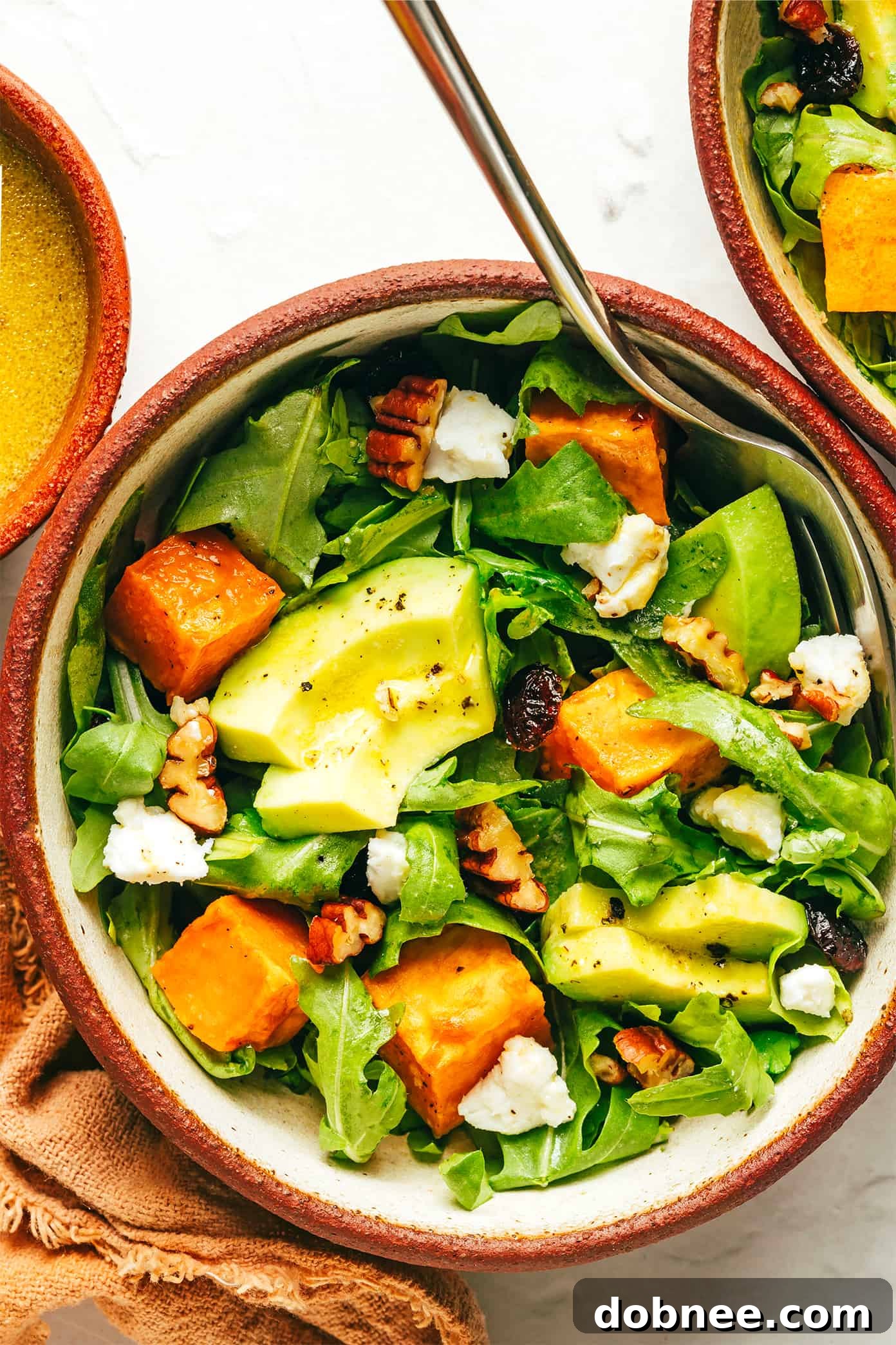 Roasted Sweet Potato and Arugula Salad: A perfect fall recipe with creamy avocado, dried cranberries, goat cheese, toasted pecans, and a zesty lemon vinaigrette. Ideal vegetarian meal or side dish.