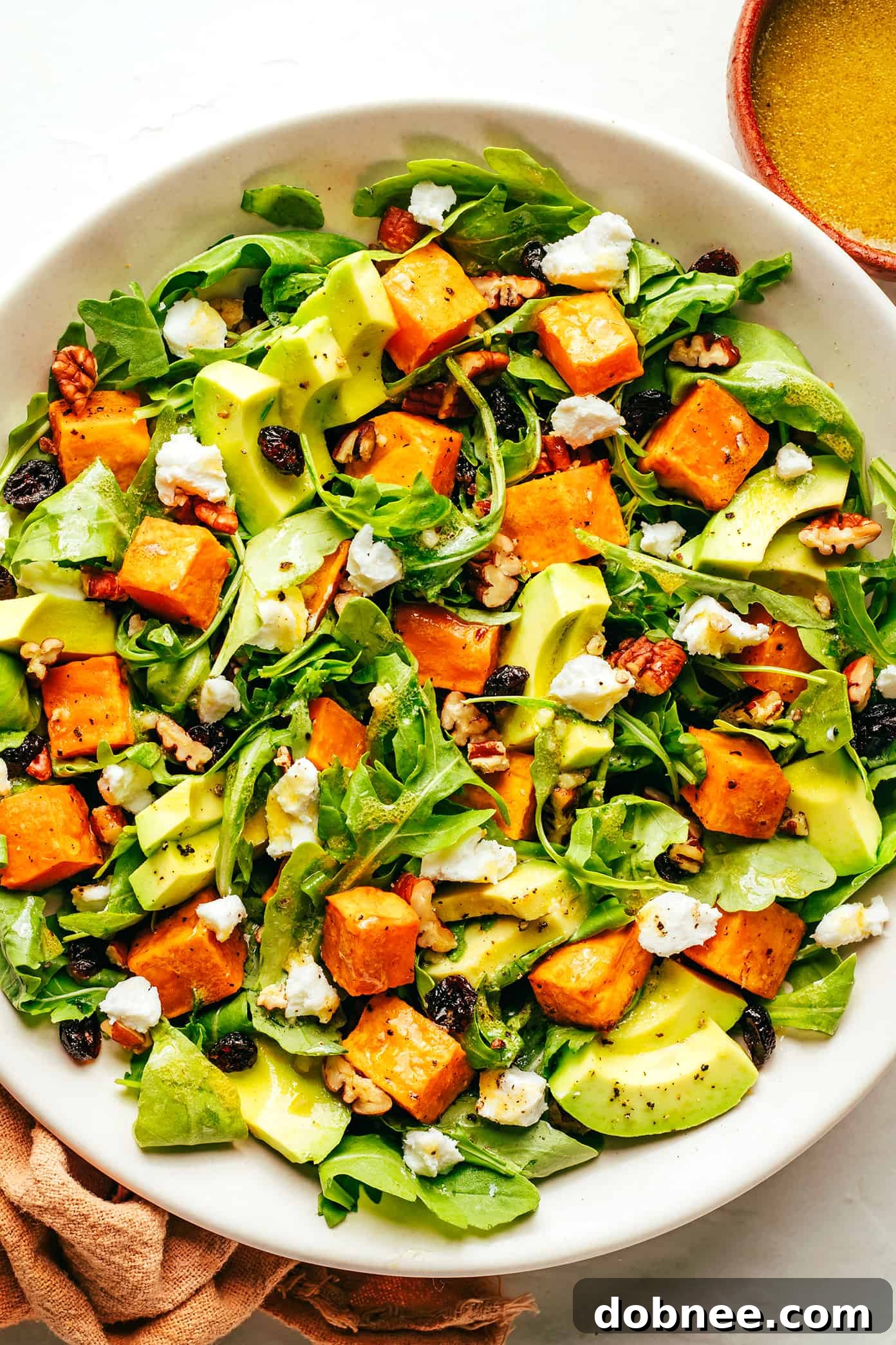 A beautifully plated bowl of Feel-Good Fall Salad, drizzled with a homemade lemon vinaigrette and ready to be served.