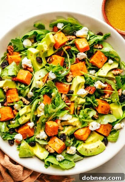 A vibrant bowl of Feel-Good Fall Salad, rich with roasted sweet potatoes, fresh arugula, creamy avocado, and crunchy pecans, drizzled with lemon vinaigrette.