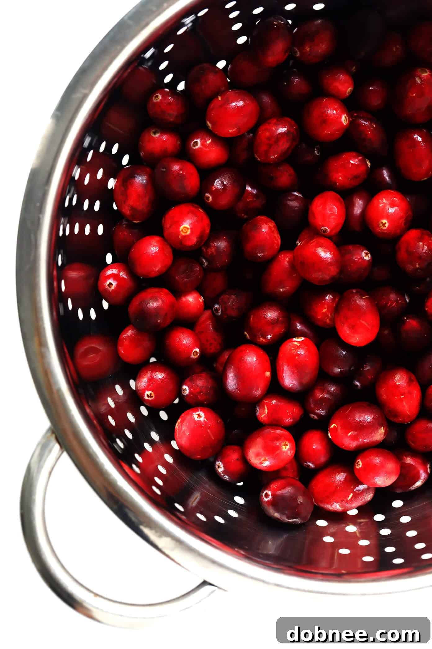 Fresh cranberries being rinsed in a colander