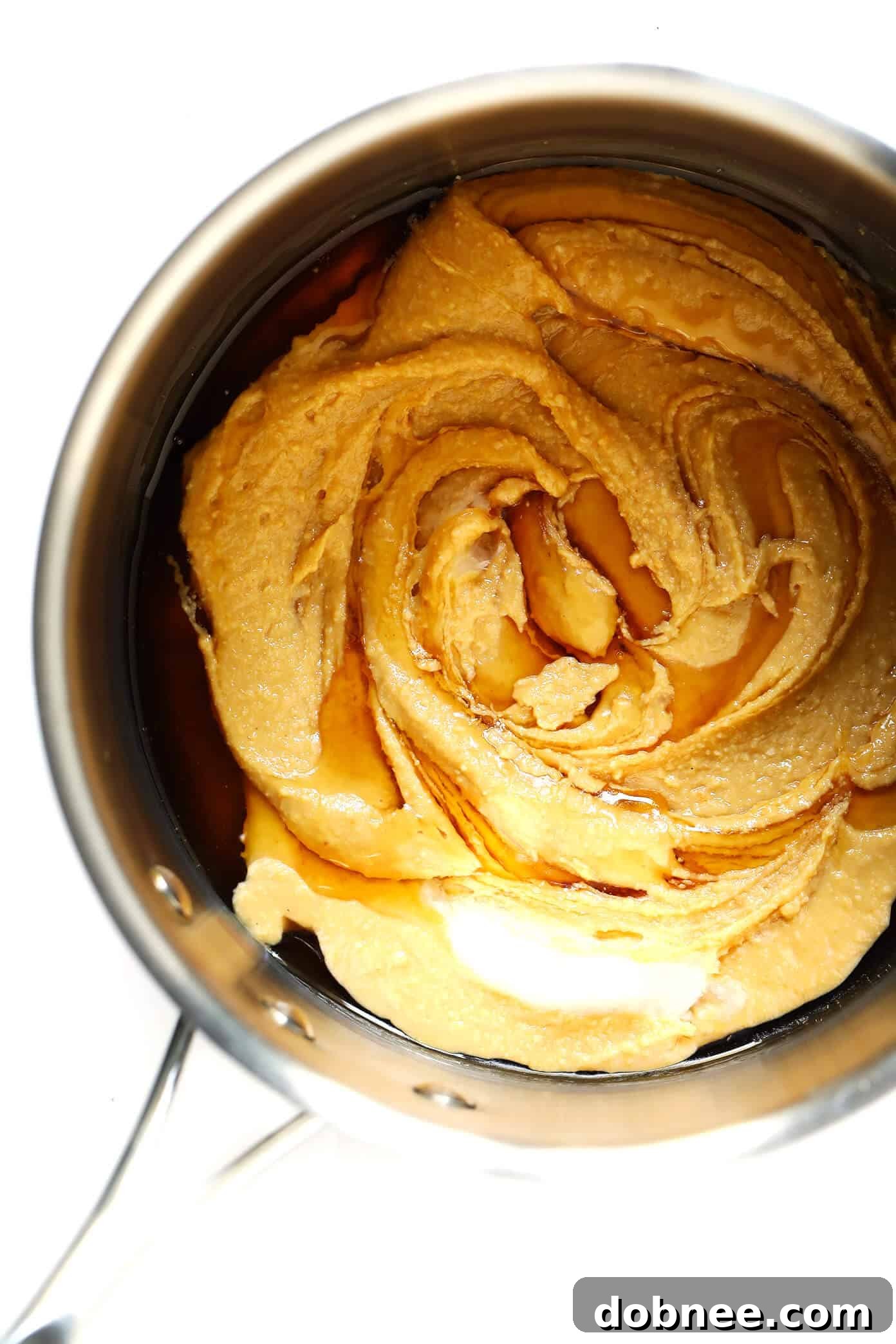 Melted natural peanut butter, honey, and coconut oil simmering in a saucepan for the granola bar base.