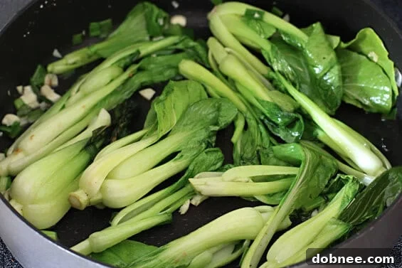 A close-up of a plate of Baby Bok Choy with Cashews, garnished with green onions.