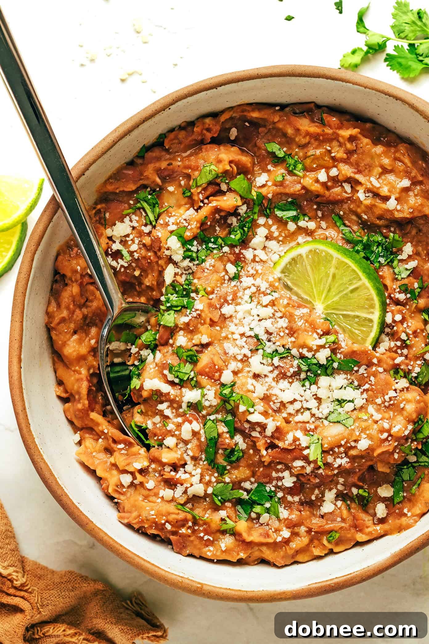 A delicious Mexican spread featuring refried beans, tortillas, various toppings, and fresh produce.