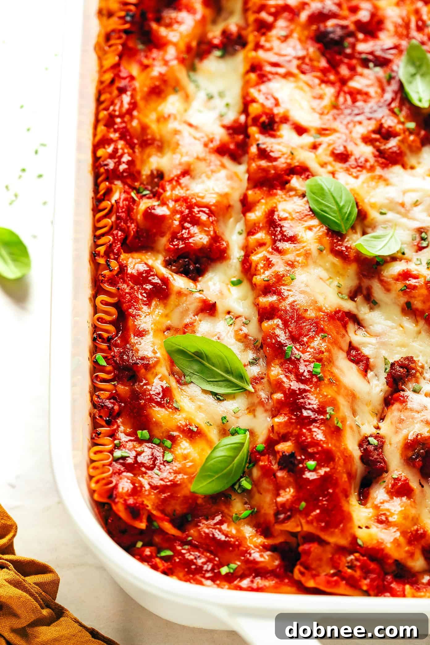 A whole baked lasagna with a golden-brown top, garnished with fresh basil leaves.