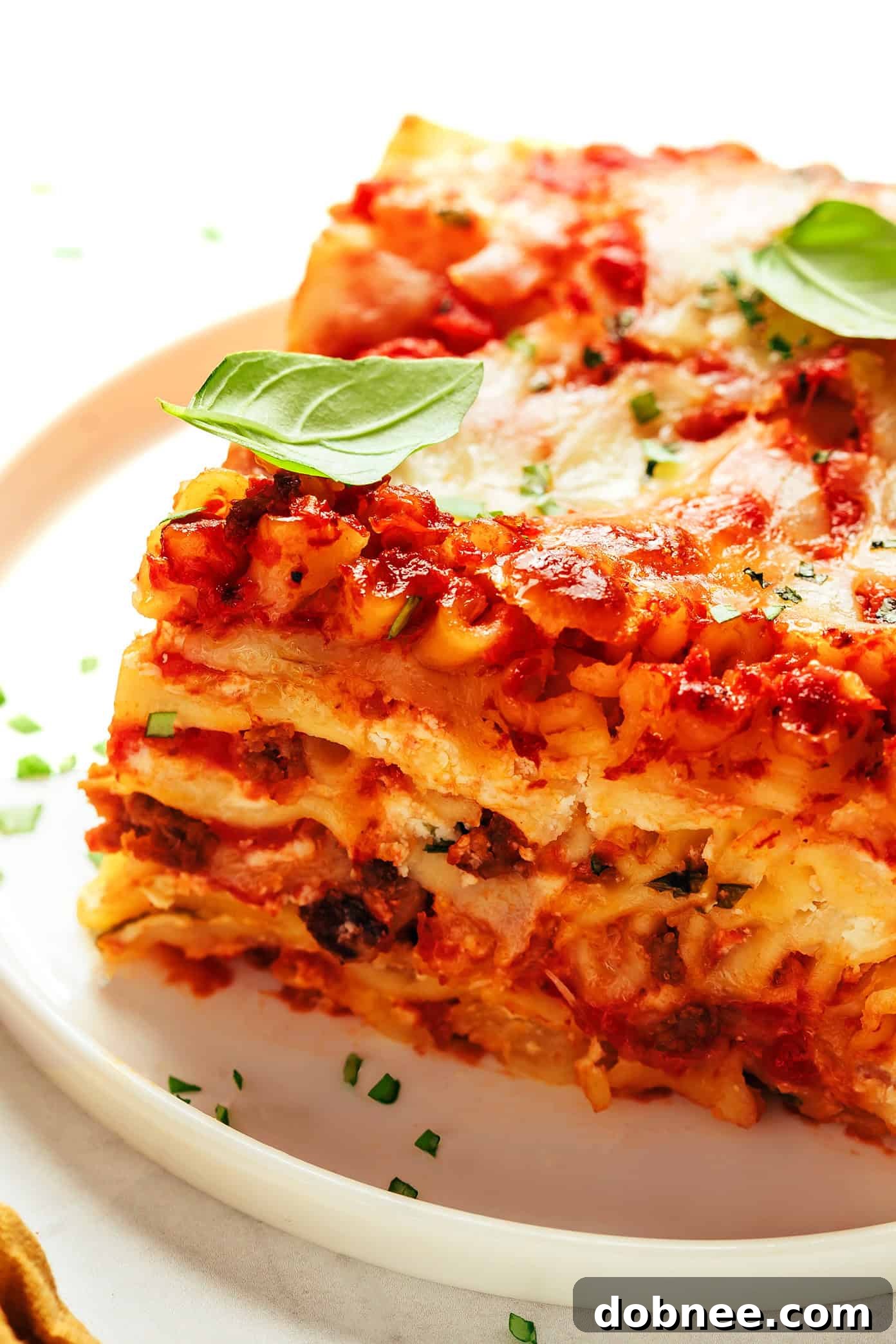 A large pan of freshly baked lasagna, sliced into generous servings, on a wooden cutting board.