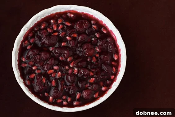 Homemade Cranberry-Pomegranate Sauce in a serving bowl, garnished with fresh cranberries and pomegranate seeds, perfect for Thanksgiving.