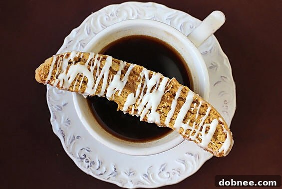 A selection of freshly baked Pumpkin Pie Biscotti, some drizzled with white chocolate, on a wooden board.