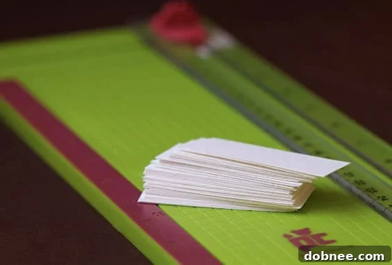 Precision Cardstock Cutting A person carefully cutting white cardstock paper into small, rectangular place card labels using a precision paper cutter for a clean finish.