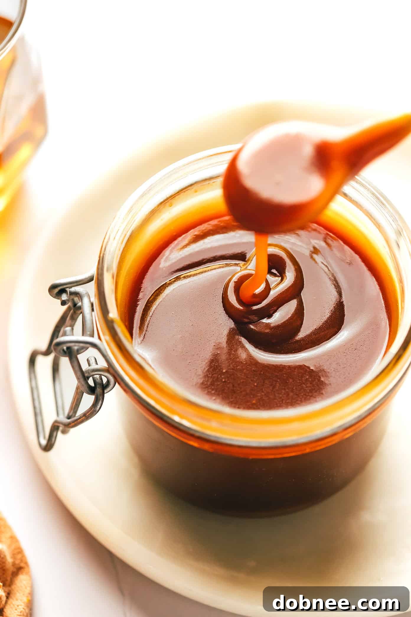 Rich, amber bourbon caramel sauce being poured, highlighting its smooth texture and glossy finish.