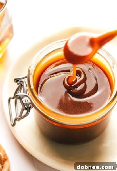 A wide shot of a glass jar filled with luscious bourbon caramel sauce, surrounded by dessert pairings.