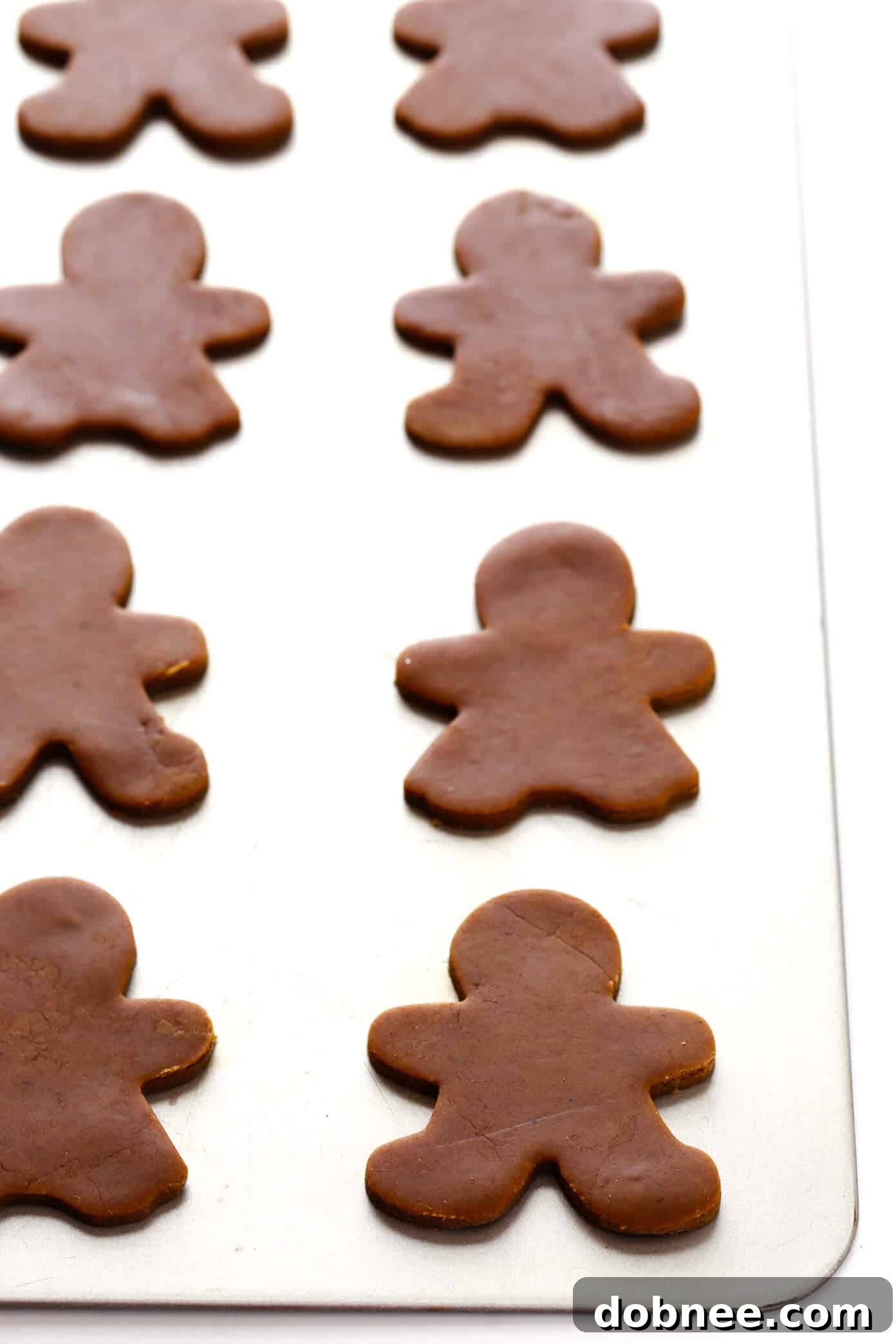 Unbaked gingerbread man cookies arranged on a baking sheet, ready for the oven.