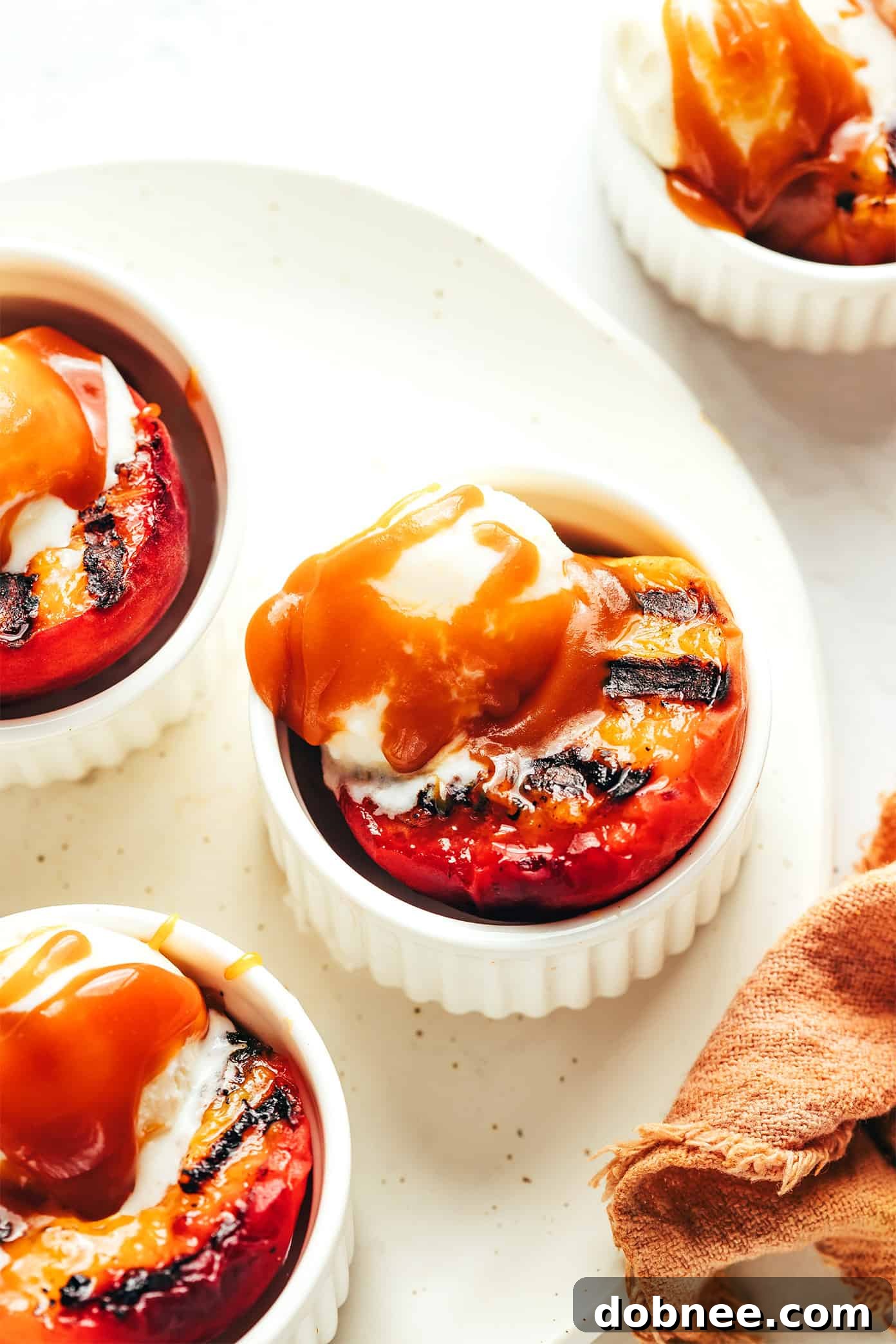 Grilled Peaches with Bourbon Caramel Sauce, featuring halved peaches on a plate with ice cream and caramel drizzle.