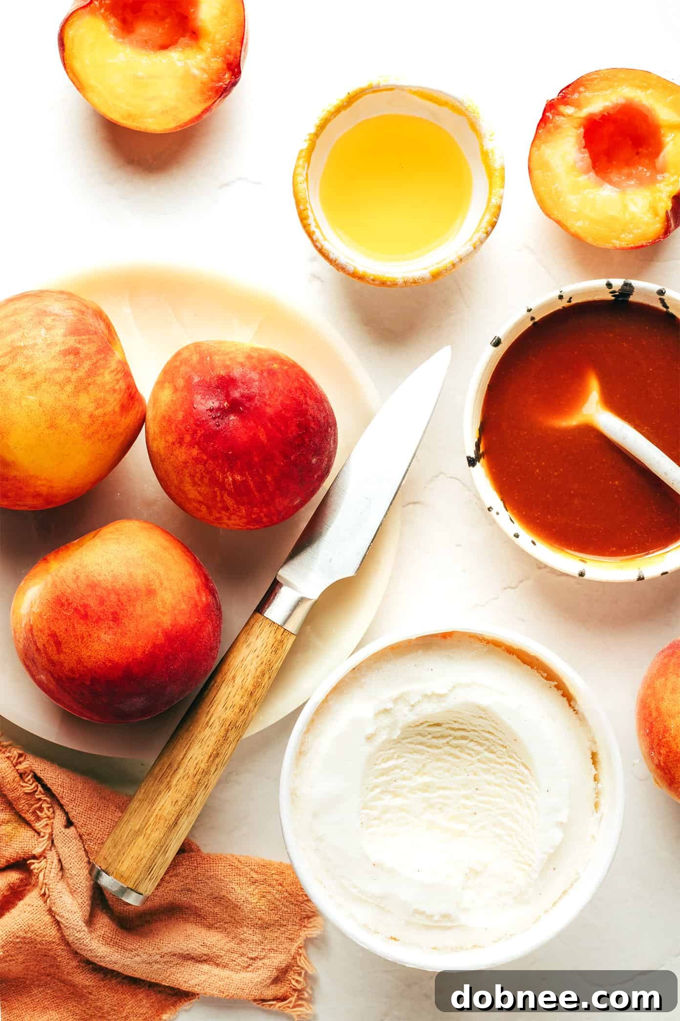 Close-up of three grilled peach halves in a bowl with vanilla ice cream and bourbon caramel sauce.