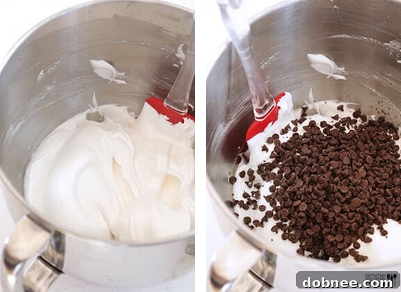 Fluffy, glossy egg white meringue batter in a stand mixer bowl, perfectly whipped to stiff peaks.