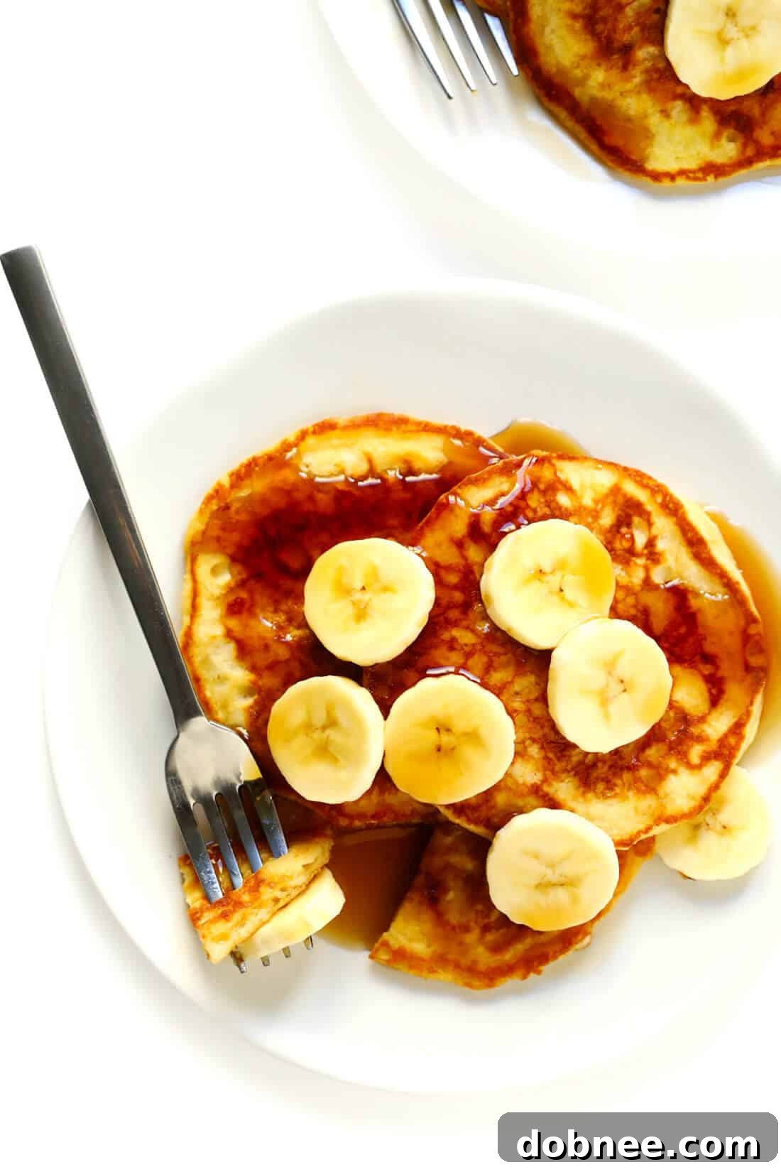 Buttermilk pancakes served with sliced bananas and maple syrup