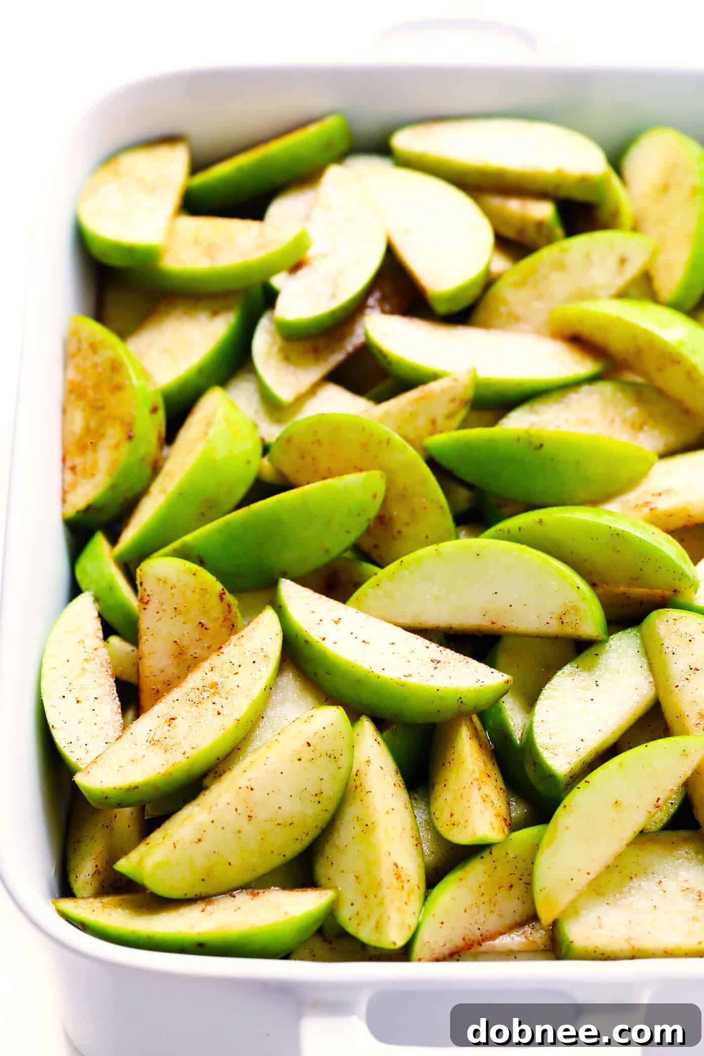 An overhead shot of an unfinished apple crisp before baking, showing the apple slices and dry topping mixture.