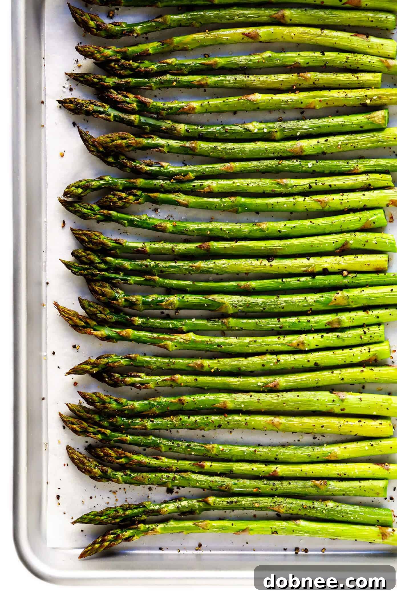 Deliciously roasted asparagus spears on a baking sheet, seasoned with olive oil, salt, and pepper, ready to be served as a healthy side dish.