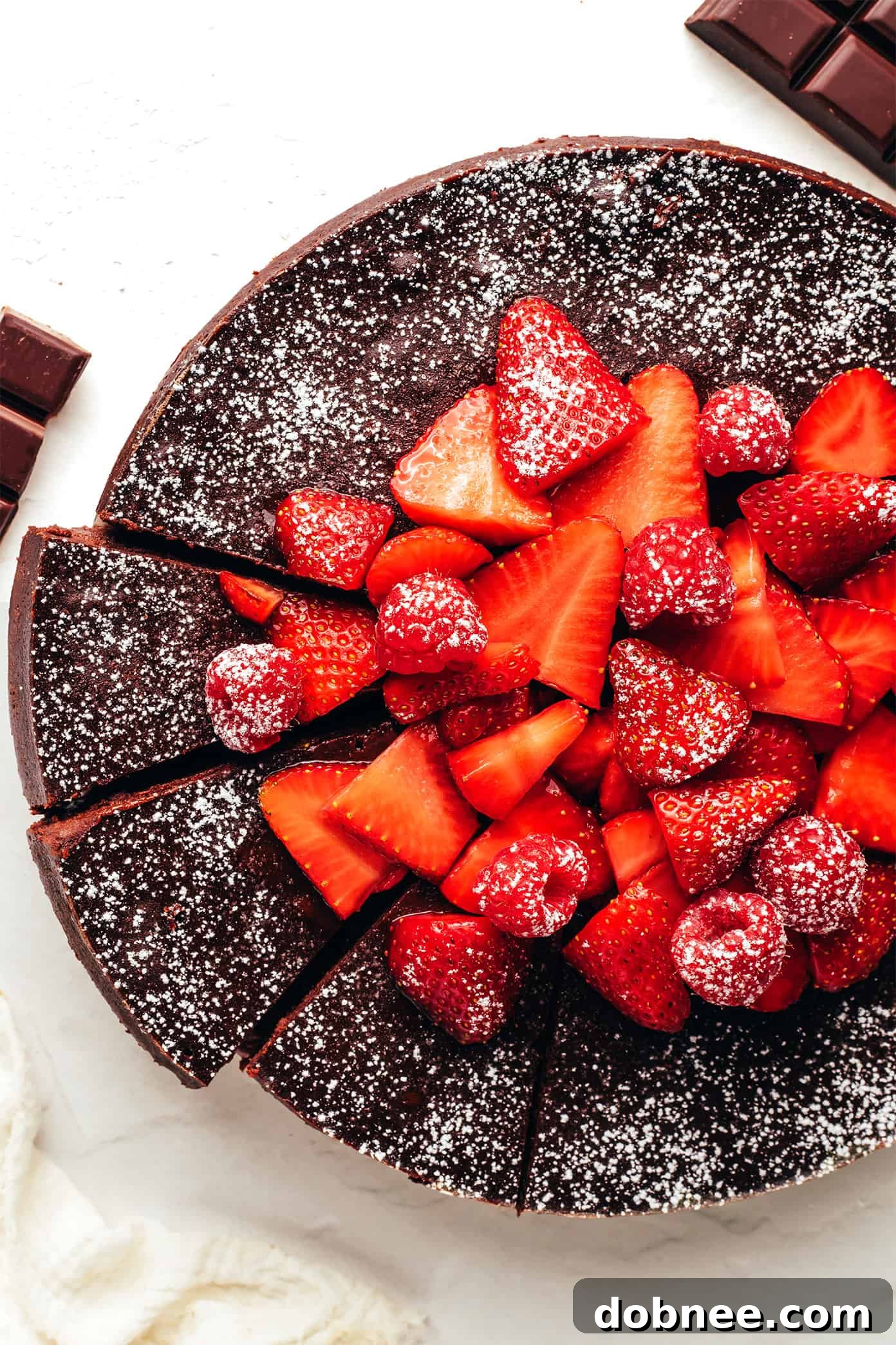 Decadent Flourless Chocolate Cake, top view, dusted with powdered sugar and fresh berries.