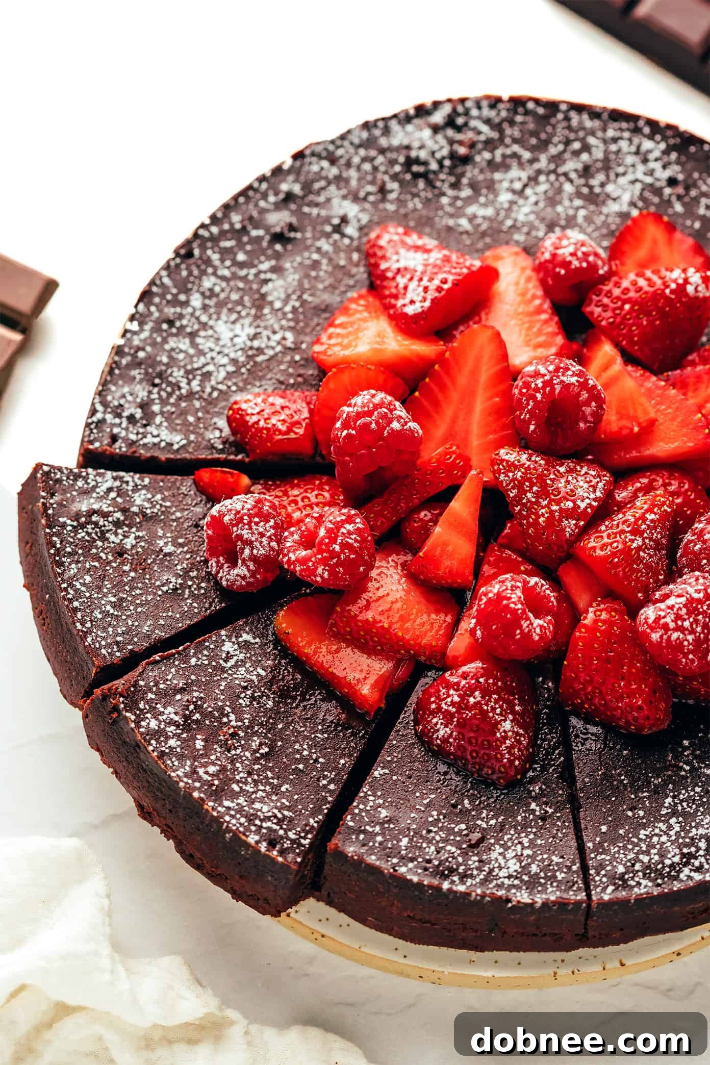 Flourless Chocolate Cake slice served with powdered sugar and raspberries.