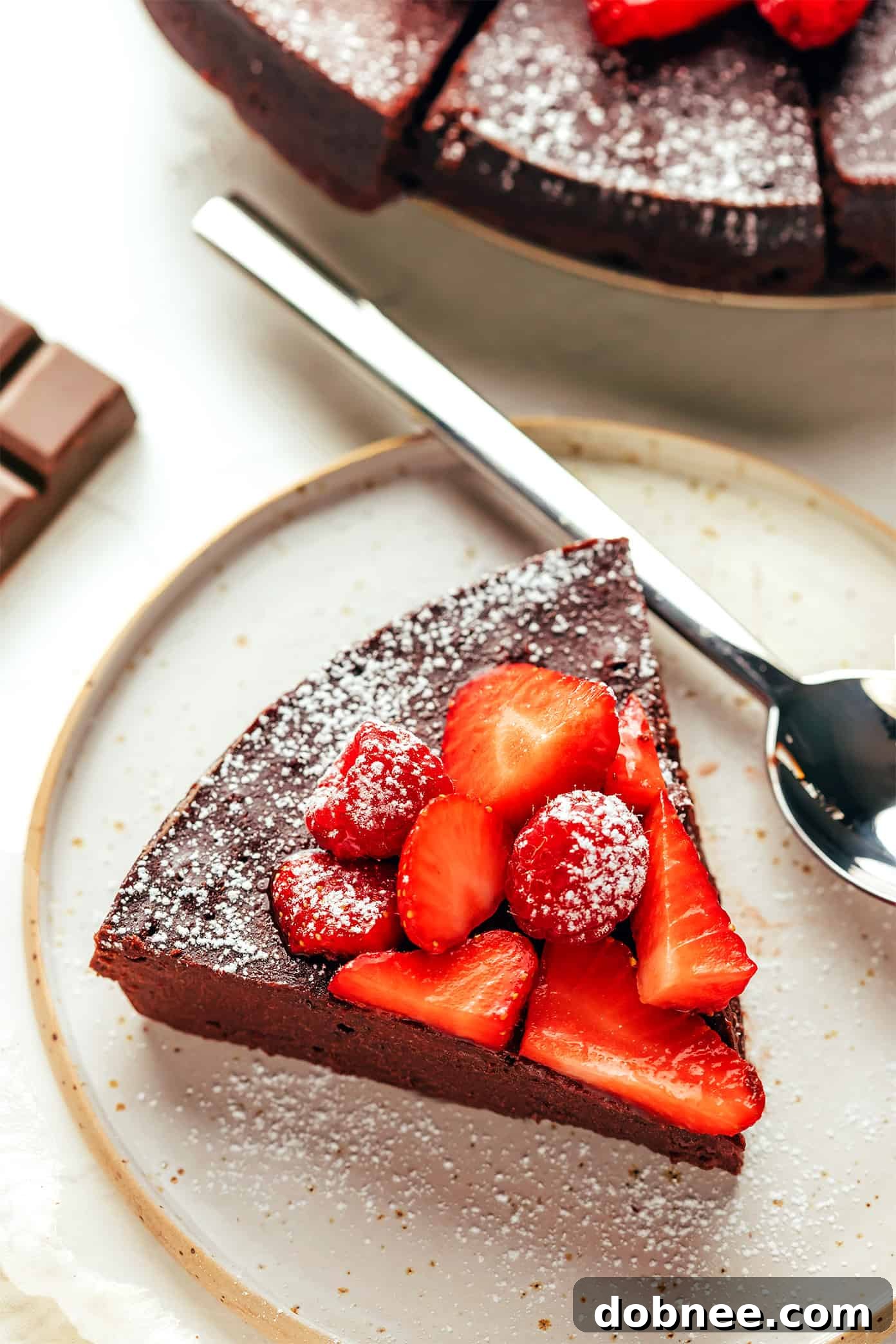 Flourless Chocolate Cake slices on plates, topped with powdered sugar and berries.