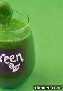 Vibrant Green Smoothie in a glass with fresh ingredients around it
