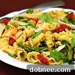 Pesto pasta with chicken, asparagus, and arugula, served in a bowl.