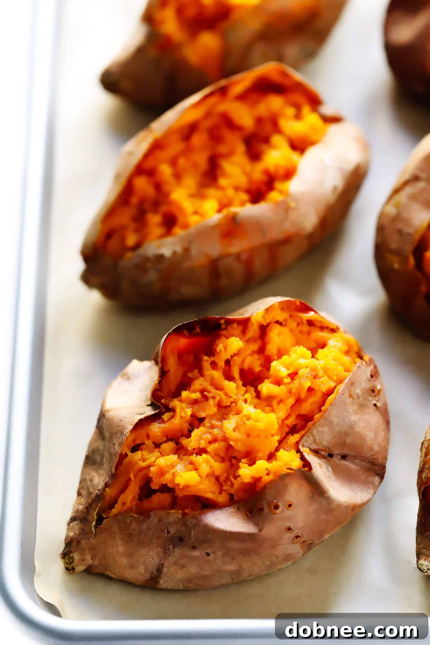 Plain baked sweet potatoes on a baking sheet, ready to be served