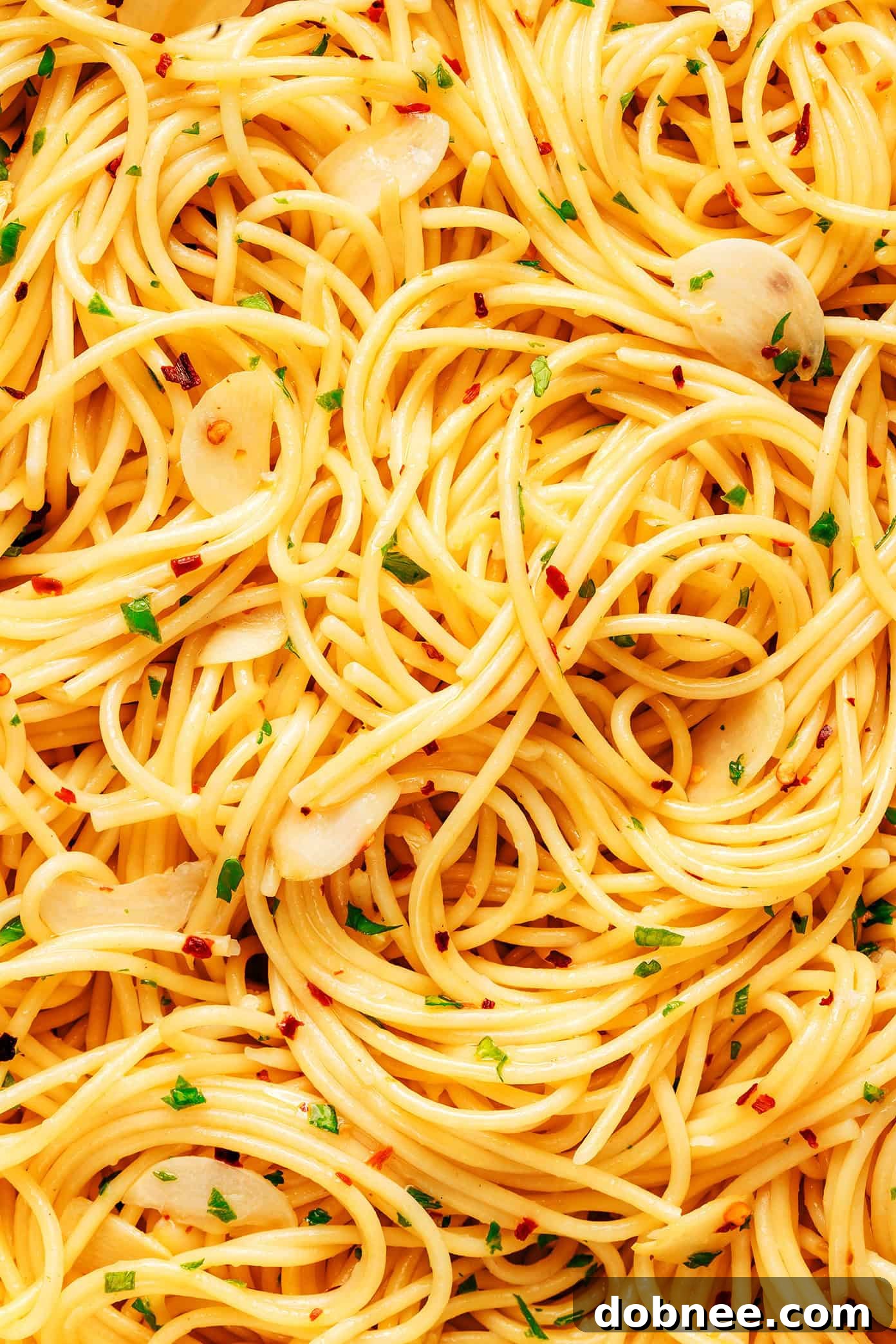 Close-up of Spaghetti Aglio e Olio being tossed in a pan, showing the glossy sauce