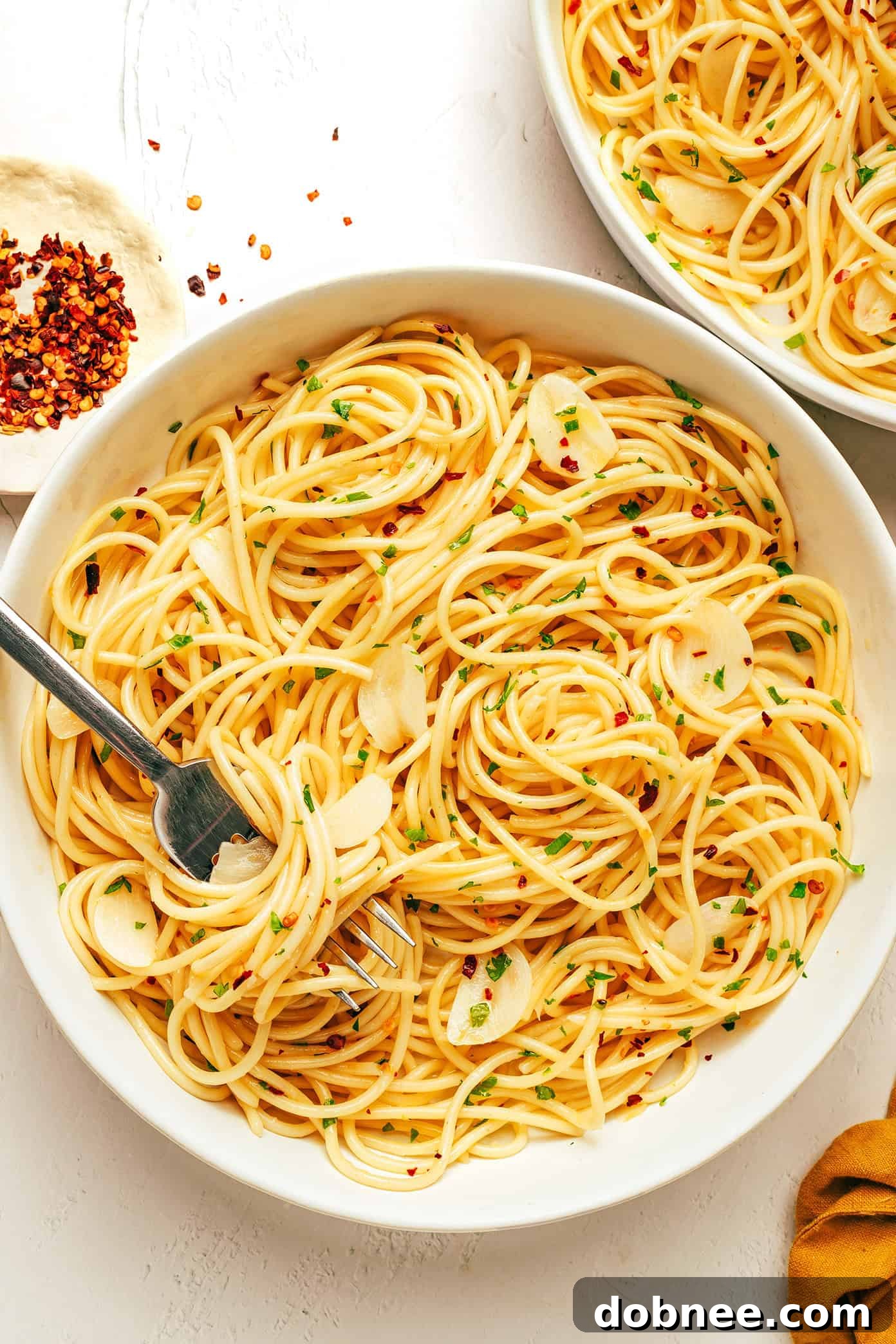 A serving of Spaghetti Aglio e Olio garnished with fresh parsley and Parmesan cheese