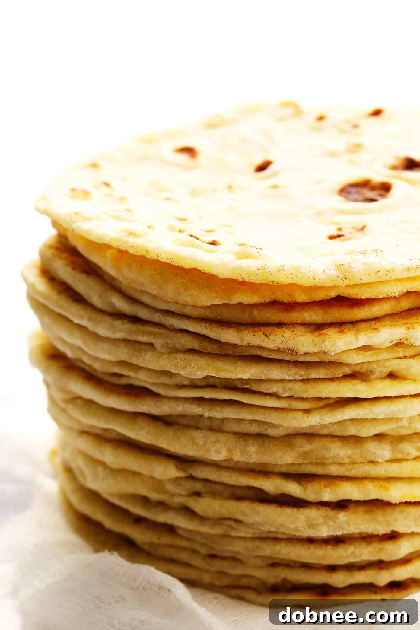 Fluffy homemade flour tortillas stacked on a board, ready to be served.