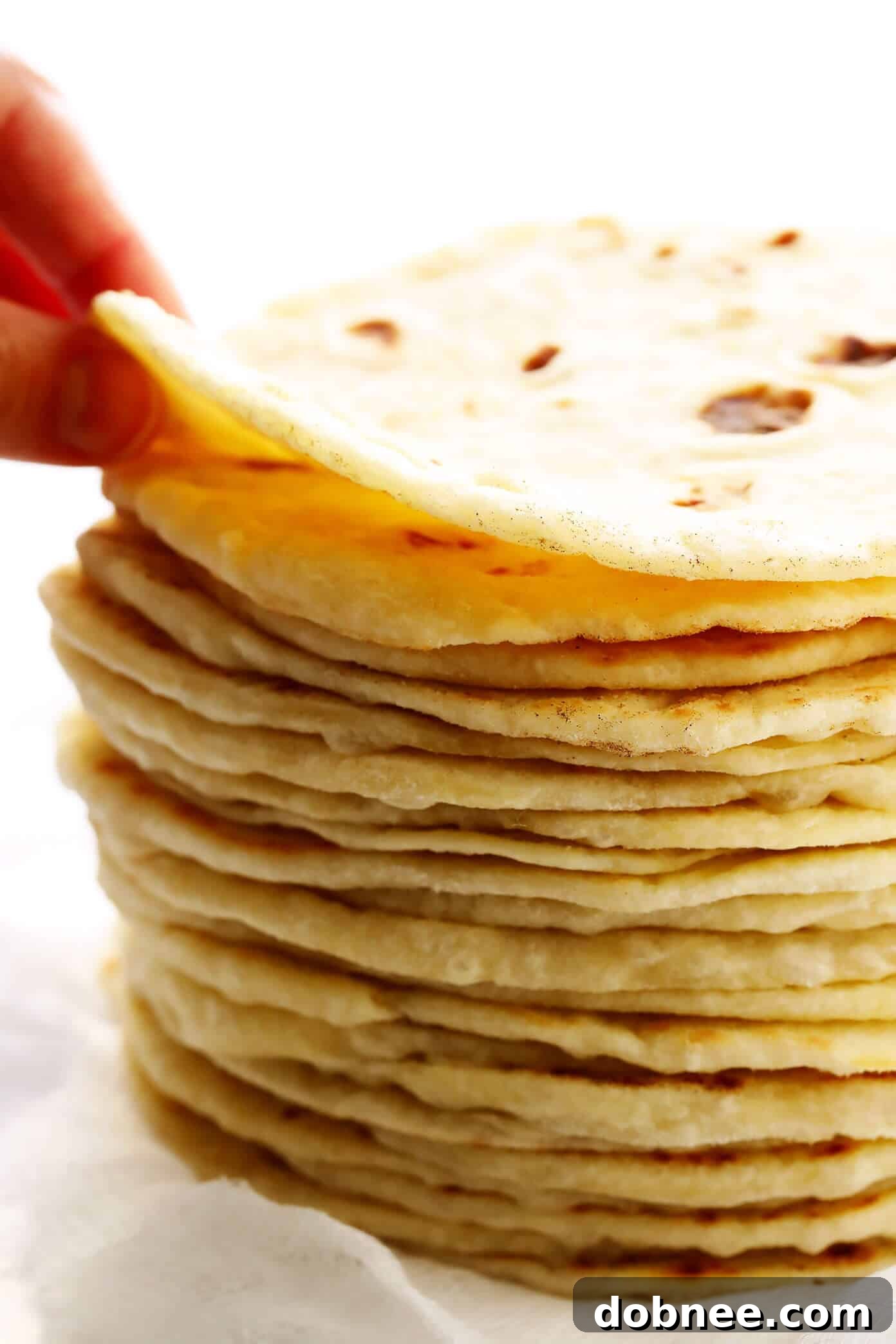 A stack of golden brown, cooked homemade flour tortillas.