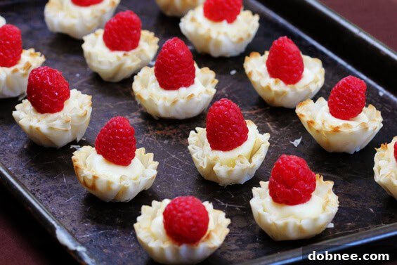 Closeup of freshly baked Brie and Raspberry Phyllo Cups on a baking sheet.