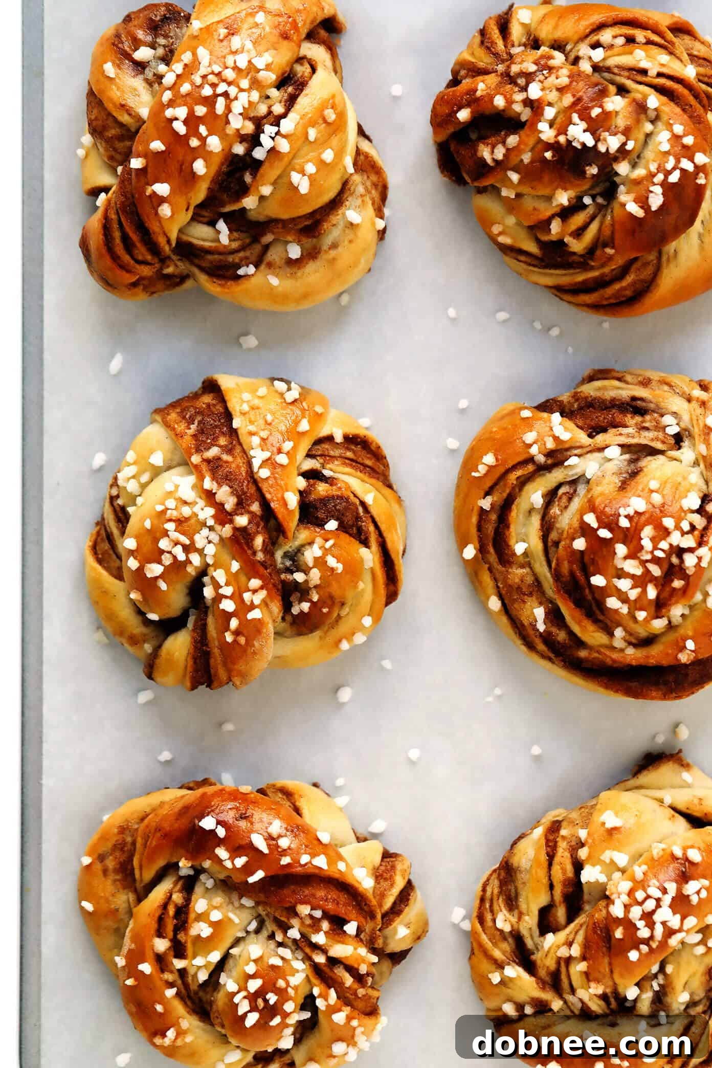 A stunning close-up of a single Swedish Cinnamon Roll (Kanelbullar) adorned with sparkling pearl sugar, highlighting its soft texture and inviting aroma.