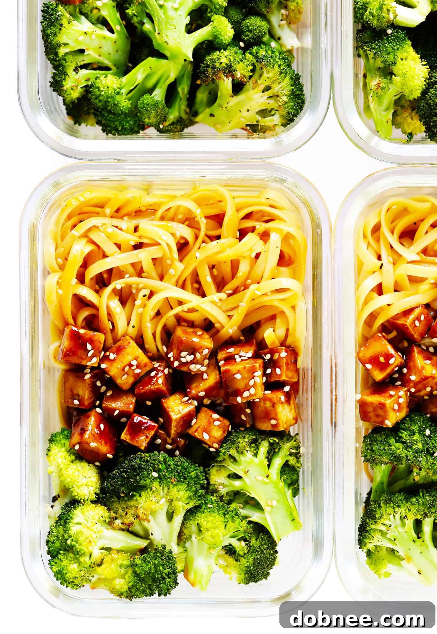 Meal prep containers filled with Five Spice Tofu Sesame Noodle Bowls, complete with roasted broccoli, ready for the week.