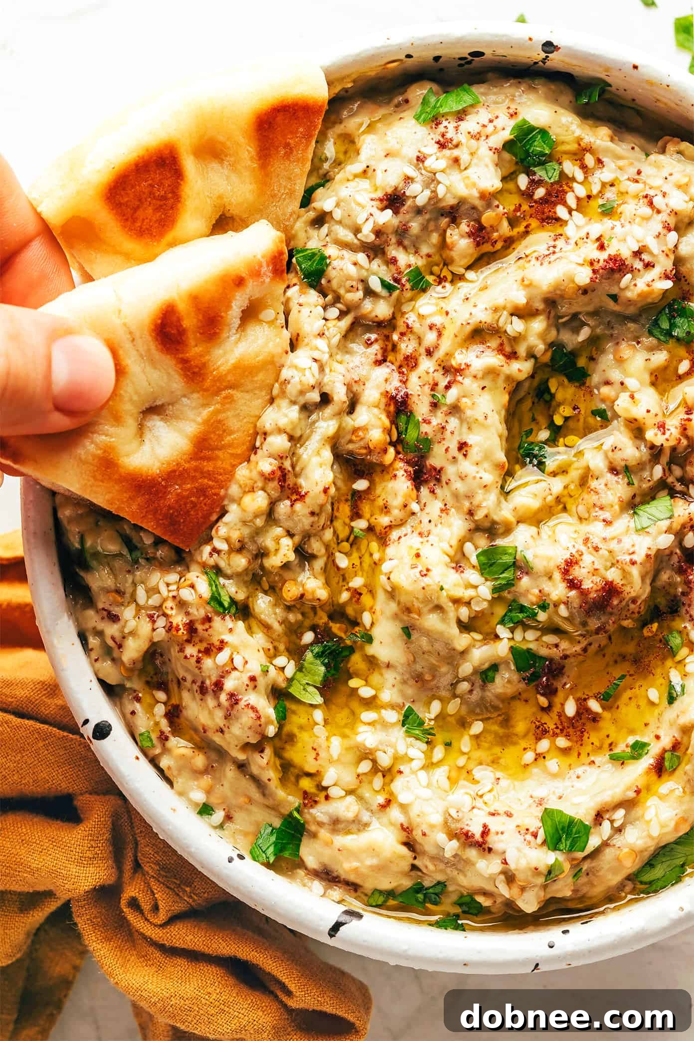 A close-up shot of creamy baba ganoush in a bowl, with a spoon scooping a portion, ready to be enjoyed.