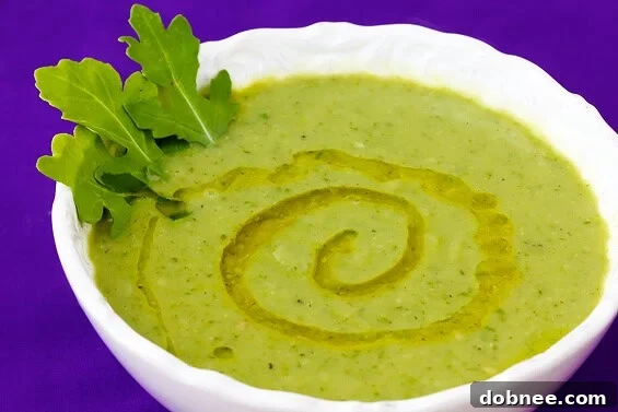 A comforting bowl of Zucchini, Arugula & White Bean Soup, garnished with fresh herbs and Parmesan cheese, perfect for a warm meal.