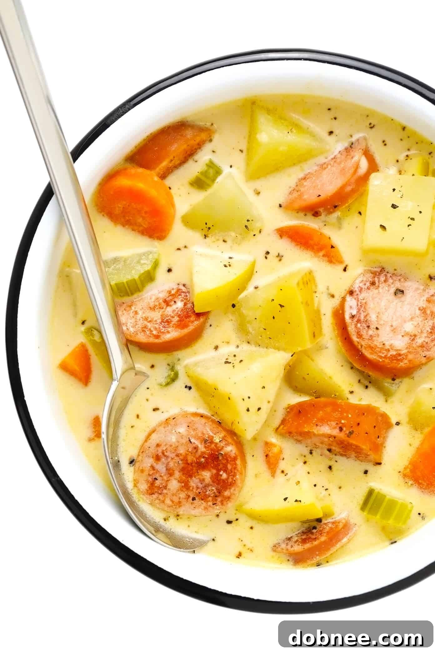 Creamy Smoked Sausage, Apple, and Potato Soup served in a bowl with a spoon, garnished with black pepper.