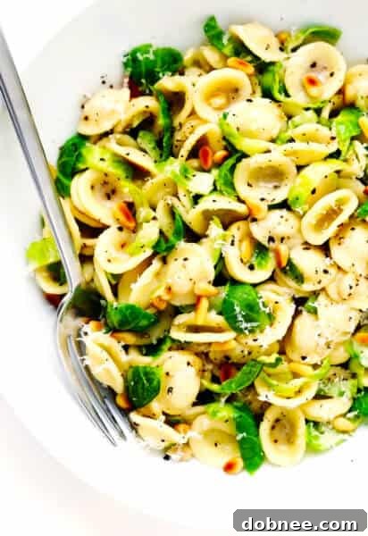 Brussels Sprouts Parmesan Pasta in a serving bowl, garnished with pine nuts.