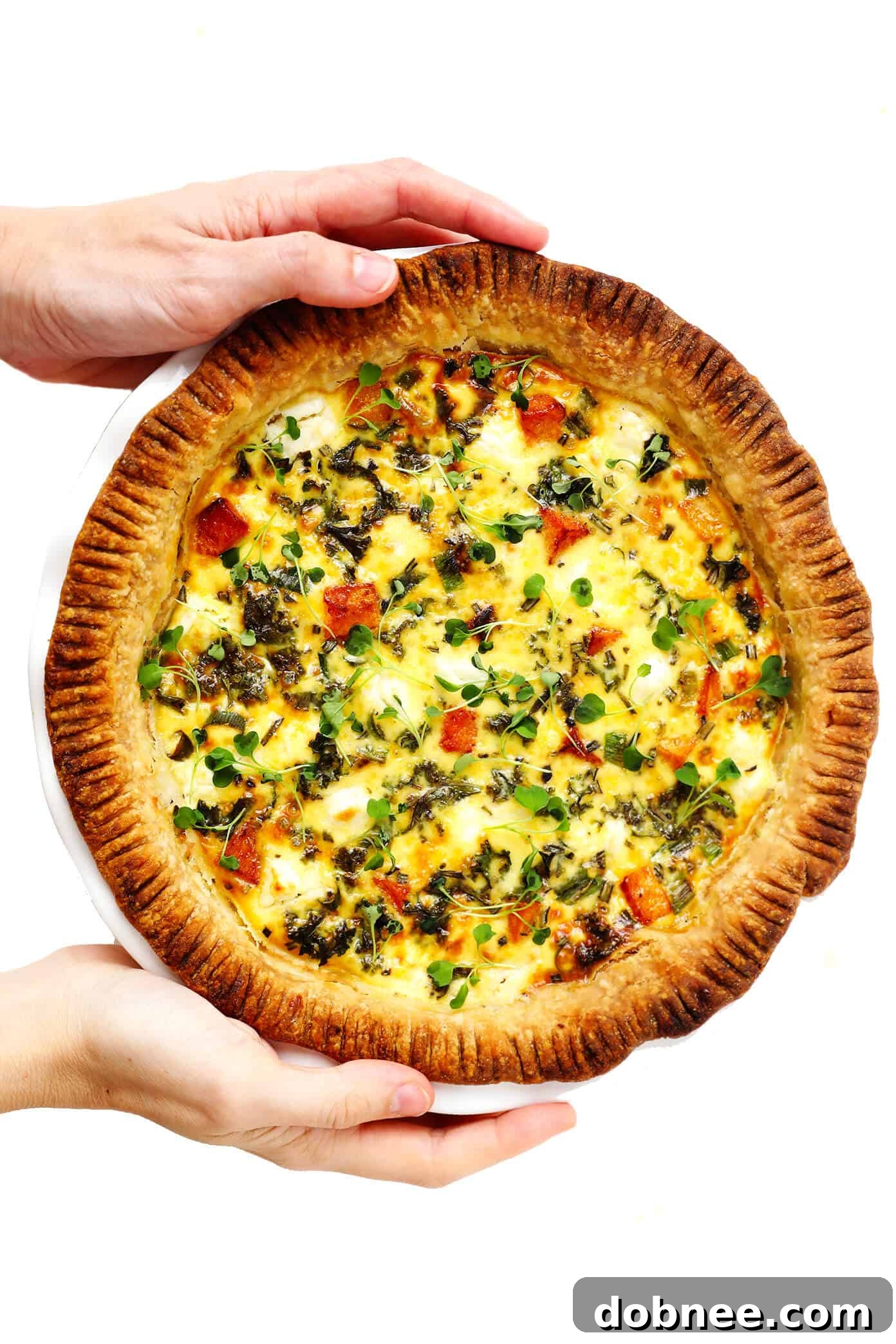Holding a whole pan of Butternut Squash, Kale and Goat Cheese Quiche