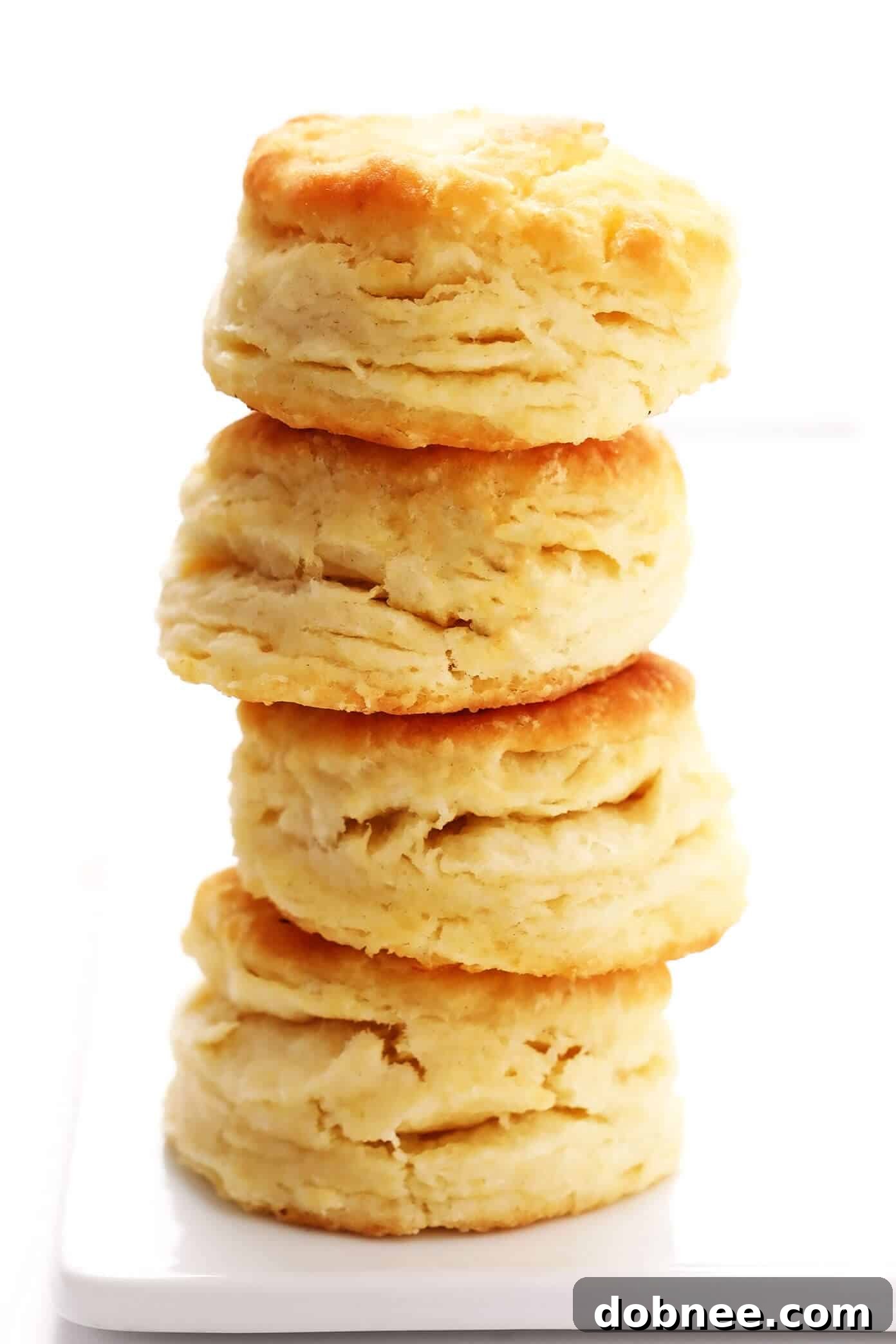 My favorite homemade buttermilk biscuit recipe -- easy to make, perfectly soft and tall and flaky, and always SO buttery and delicious. Serve them for breakfast with jam or gravy, as a side dish for lunch or dinner, or as a topping for chicken pot pie or your favorite casserole! These fluffy, golden biscuits are a true comfort food delight. | gimmesomeoven.com #biscuit #roll #bread #recipe #buttermilk #breakfast #brunch #side #vegetarian #baking Fluffy homemade buttermilk biscuits stacked on a wooden board