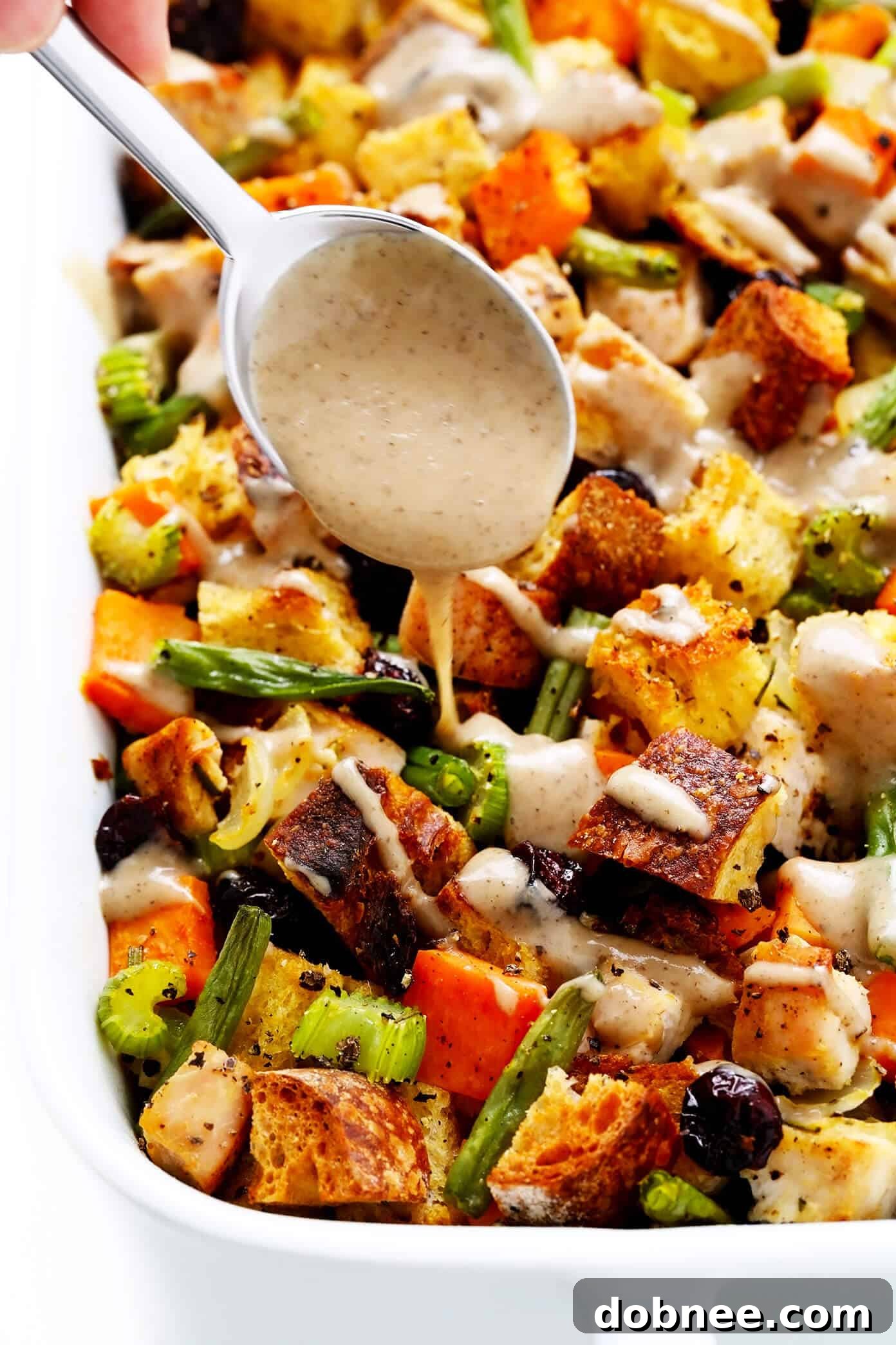 Drizzling Gravy on Thanksgiving Casserole, showcasing the rich, golden-brown top of the baked dish.